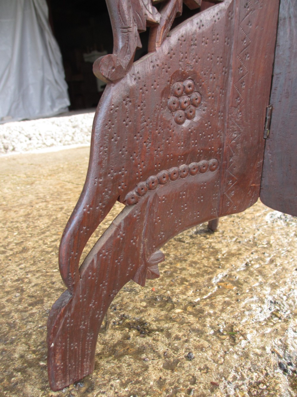 An Anglo-Indian carved teak occasional table with a scalloped circular top, floral inlay centre, and a folding fretted base. View VIII