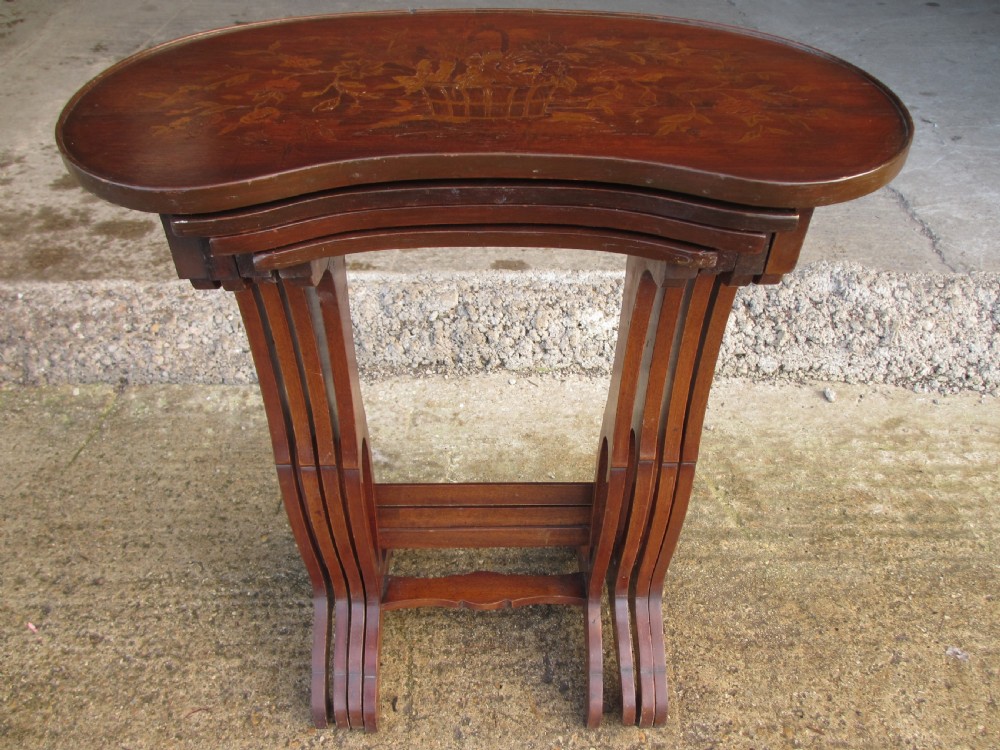 A set of four nested mahogany side tables featuring kidney-shaped tops with floral marquetry inlay.