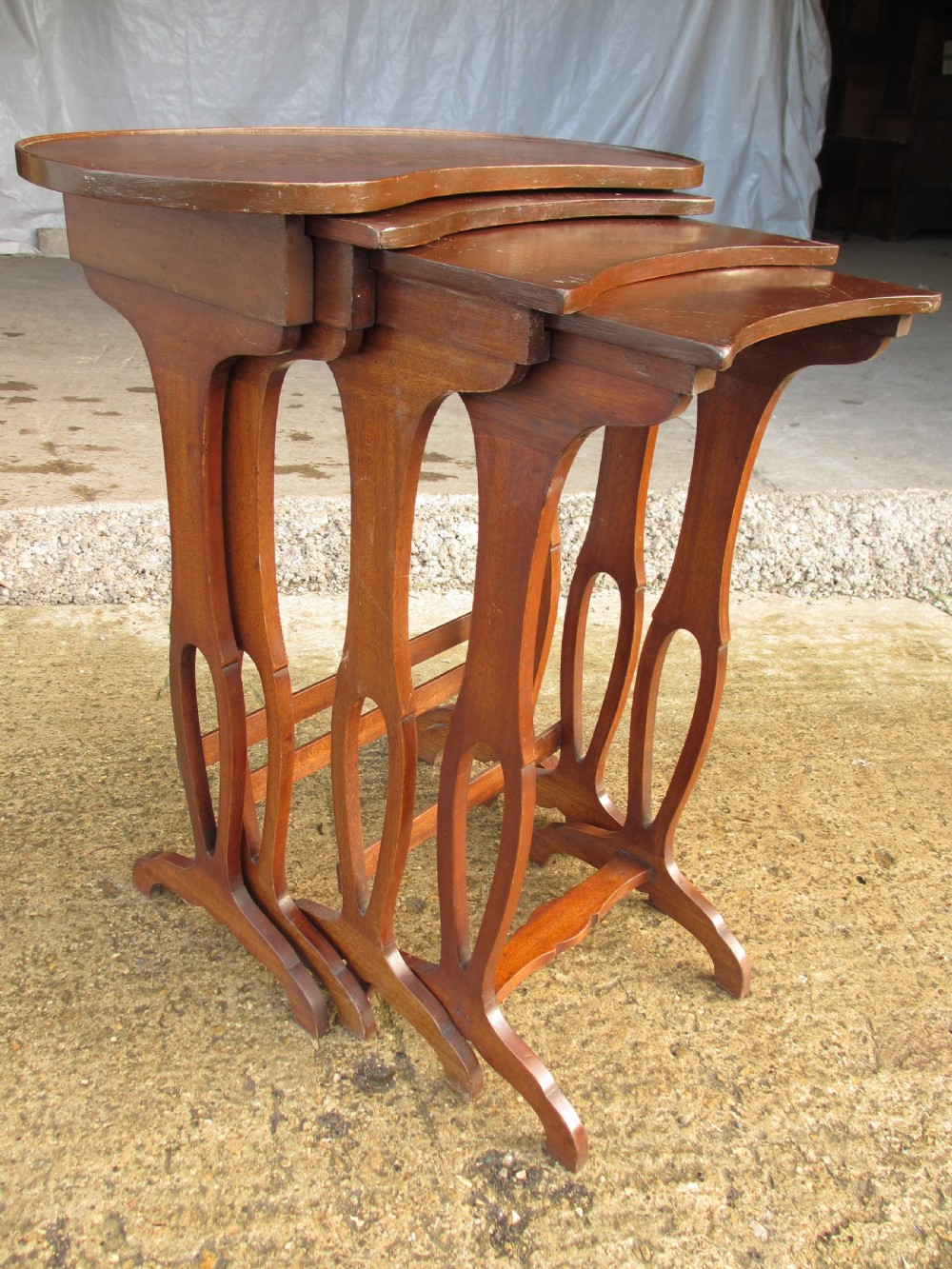 A set of four nested mahogany side tables featuring kidney-shaped tops with floral marquetry inlay. View VIII