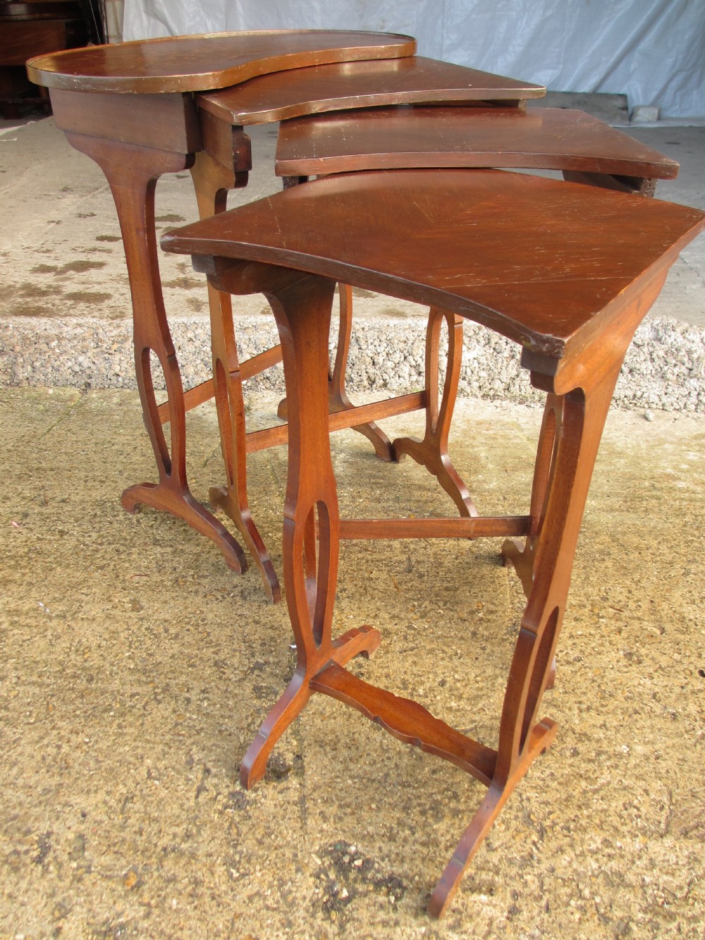 A set of four nested mahogany side tables featuring kidney-shaped tops with floral marquetry inlay. View IX