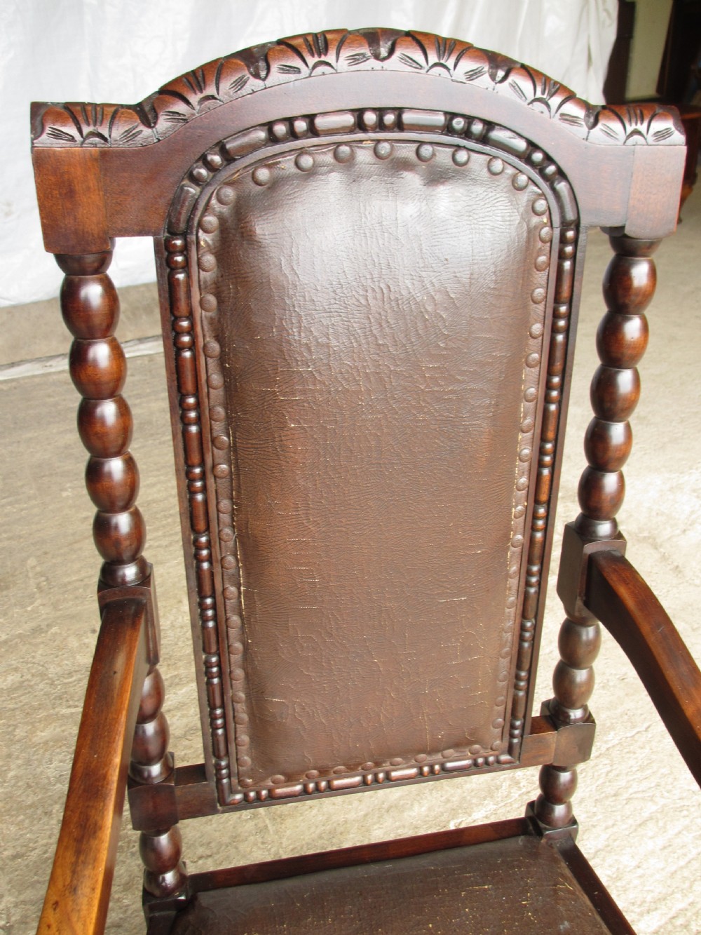 An Arts and Crafts mahogany carver armchair featuring bobbin-turned legs, curved armrests, a carved top crest, and brown studded leather upholstery. View IV
