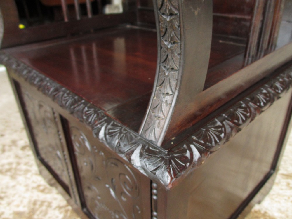 A pair of carved dark mahogany panelled box settles featuring decorative diamond back panels and scrolling foliate carved storage bases. View X