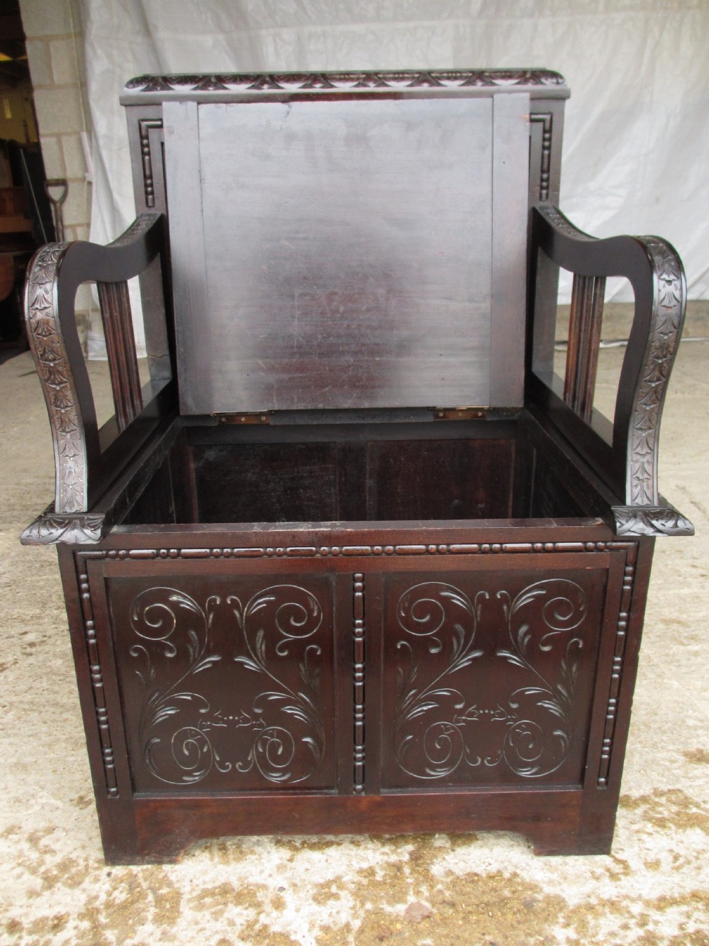 A pair of carved dark mahogany panelled box settles featuring decorative diamond back panels and scrolling foliate carved storage bases. View XI