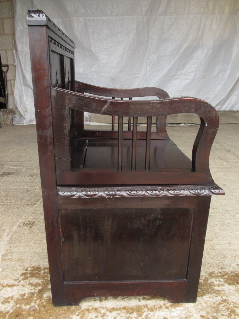 A pair of carved dark mahogany panelled box settles featuring decorative diamond back panels and scrolling foliate carved storage bases. View XII