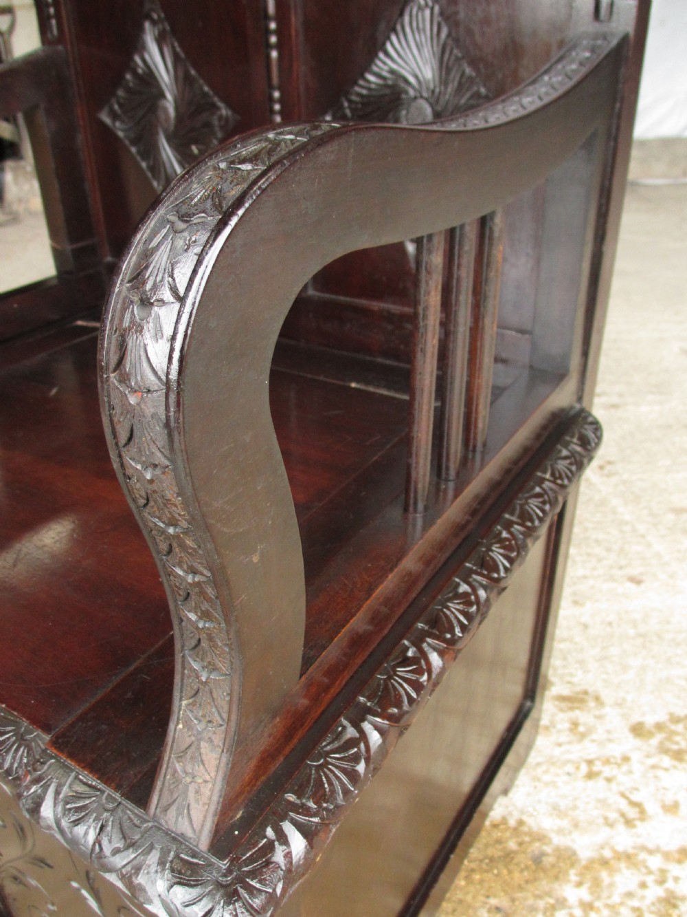A pair of carved dark mahogany panelled box settles featuring decorative diamond back panels and scrolling foliate carved storage bases. View XXI