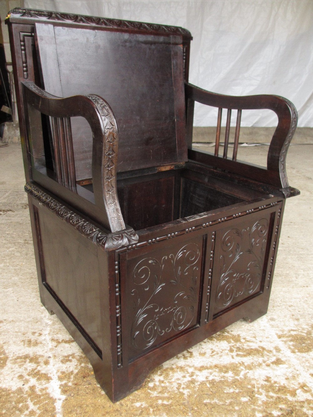 A pair of carved dark mahogany panelled box settles featuring decorative diamond back panels and scrolling foliate carved storage bases. View XXII
