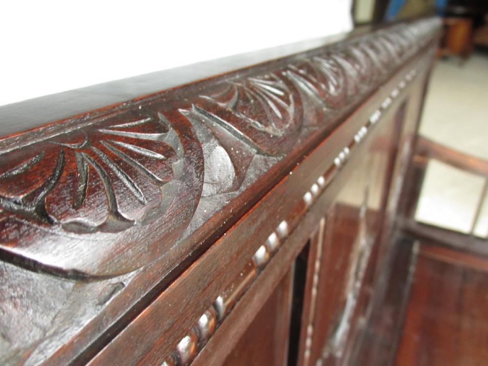 A dark mahogany panelled box settle featuring carved lozenge motifs on the backrest and foliate carving on the front panels. View III