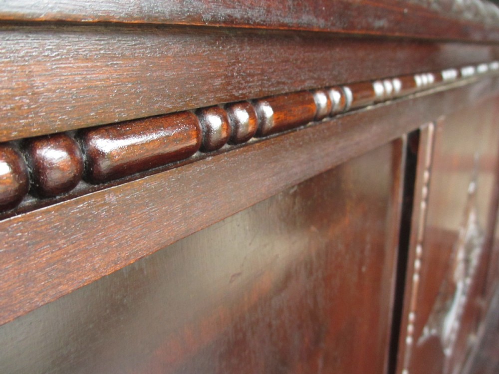 A dark mahogany panelled box settle featuring carved lozenge motifs on the backrest and foliate carving on the front panels. View IV