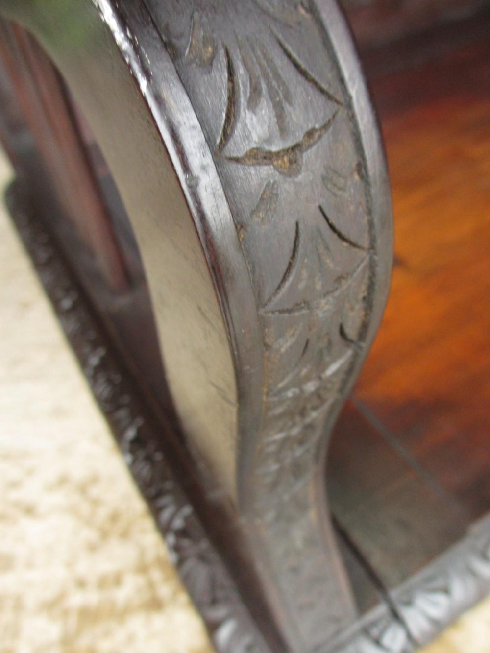 A dark mahogany panelled box settle featuring carved lozenge motifs on the backrest and foliate carving on the front panels. View V