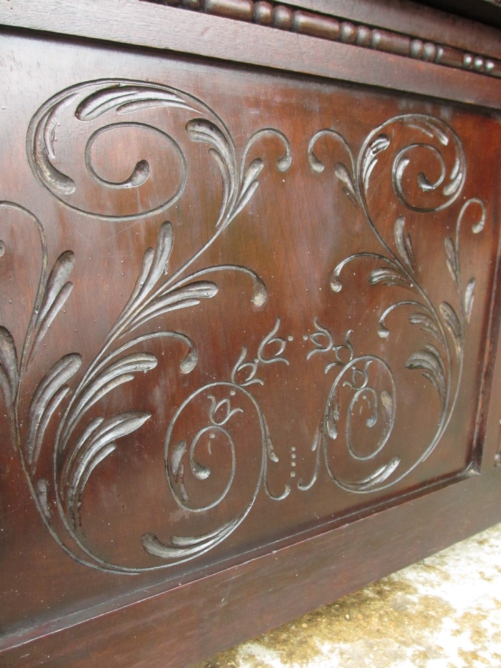 A dark mahogany panelled box settle featuring carved lozenge motifs on the backrest and foliate carving on the front panels. View IX