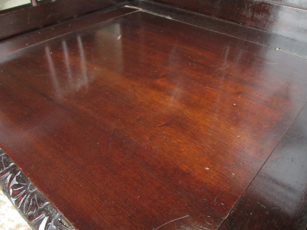 A dark brown carved mahogany box settle featuring a high panelled back with diamond motifs, curved armrests, and a hinged storage base decorated with foliate carvings. View VIII