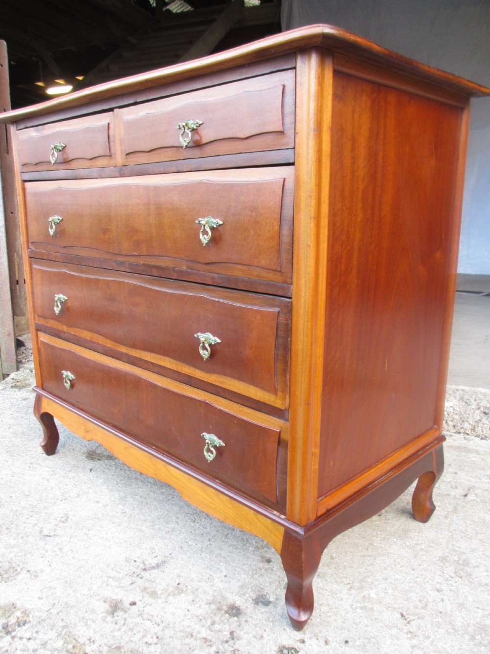 A warm brown mahogany chest of drawers featuring five drawers with brass handles and curved cabriole legs. View III
