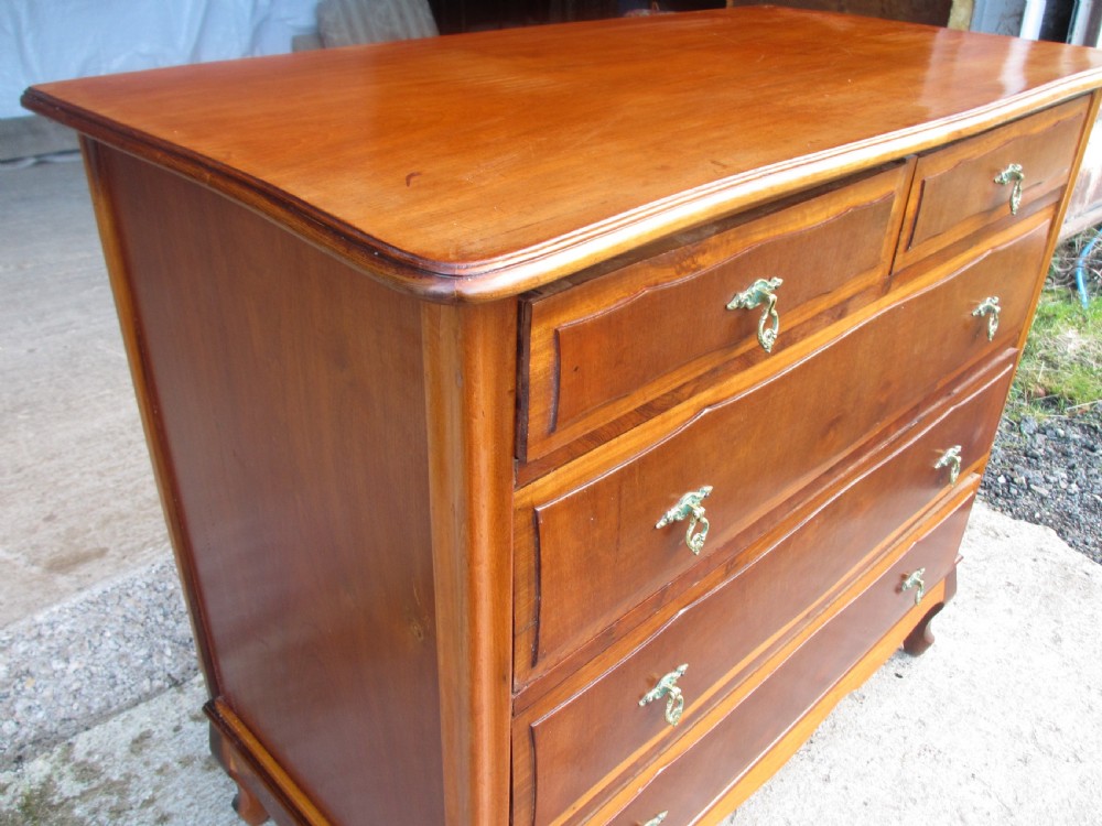 A warm brown mahogany chest of drawers featuring five drawers with brass handles and curved cabriole legs. View IV