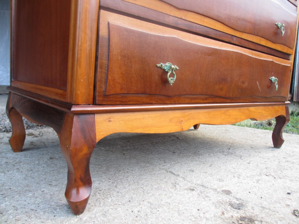 A warm brown mahogany chest of drawers featuring five drawers with brass handles and curved cabriole legs. View VII