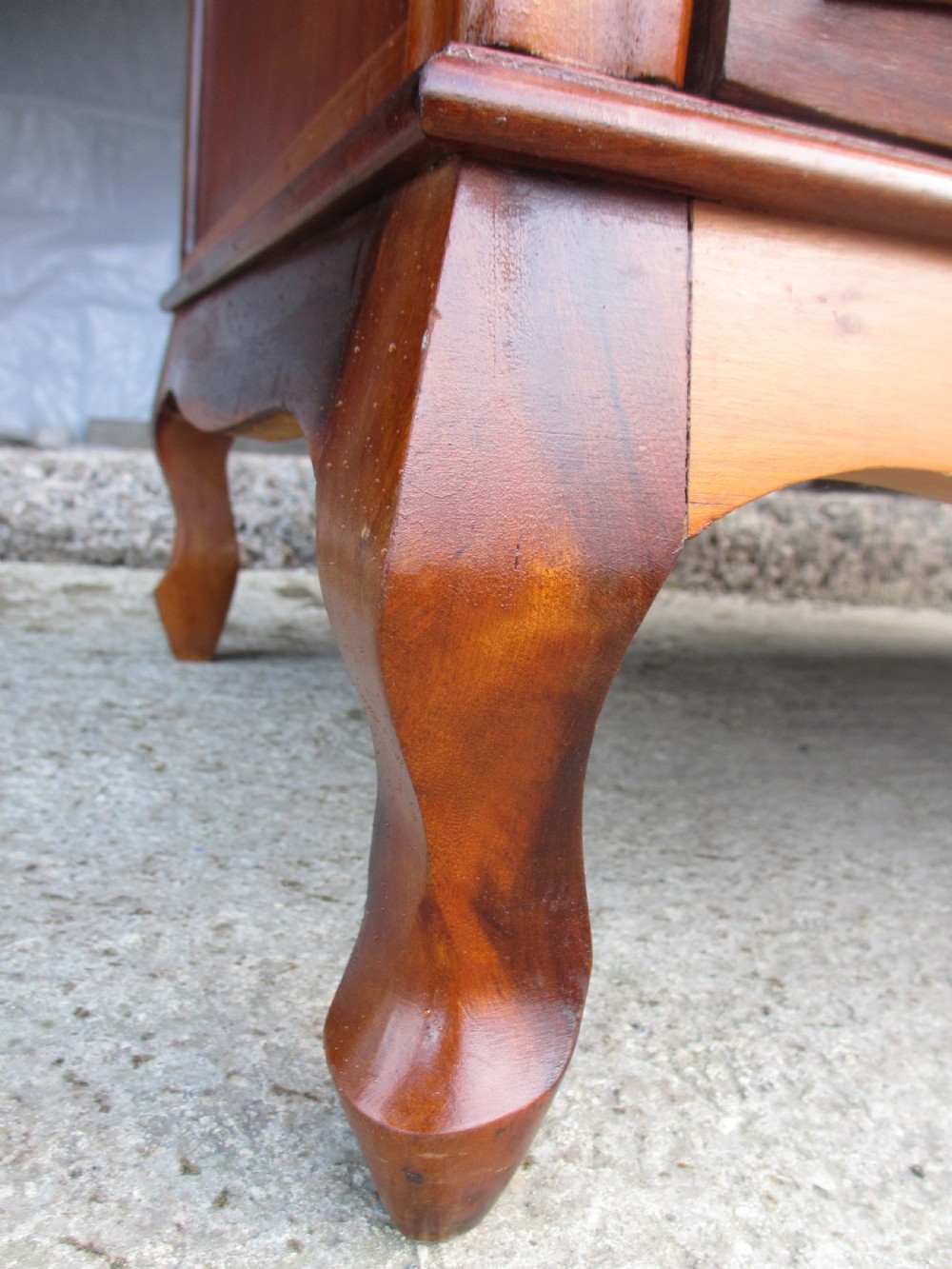 A warm brown mahogany chest of drawers featuring five drawers with brass handles and curved cabriole legs. View VIII