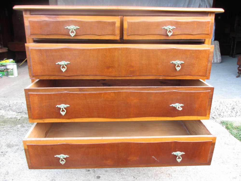 A warm brown mahogany chest of drawers featuring five drawers with brass handles and curved cabriole legs. View IX
