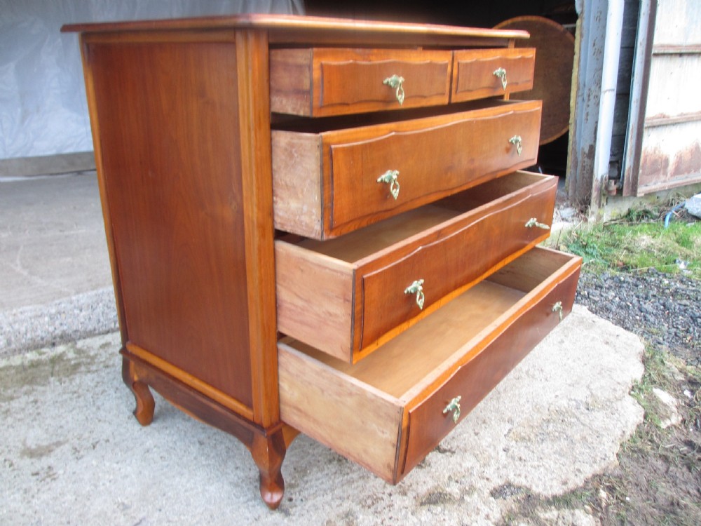 A warm brown mahogany chest of drawers featuring five drawers with brass handles and curved cabriole legs. View X