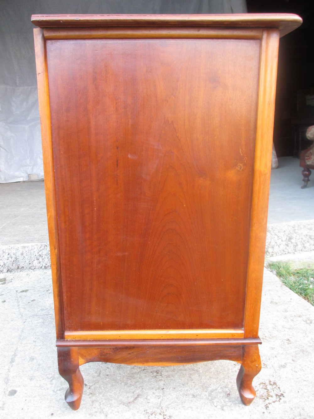 A warm brown mahogany chest of drawers featuring five drawers with brass handles and curved cabriole legs. View XI