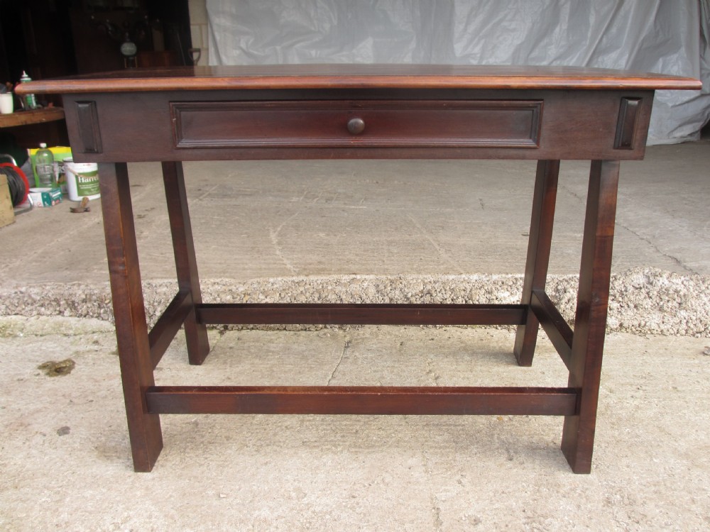 A dark mahogany wooden side table featuring a single frieze drawer with a wooden knob handle and lower cross stretchers.