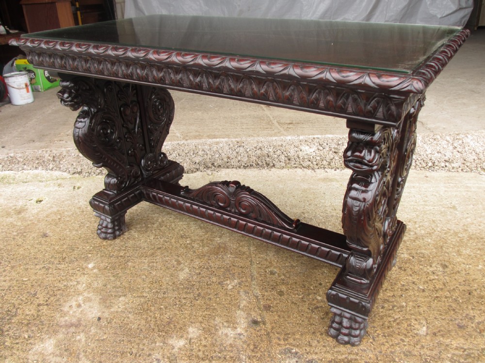 Carved dark mahogany centre console table featuring scroll supports with carved grotesque figures, a decorated stretcher, and claw feet. View II