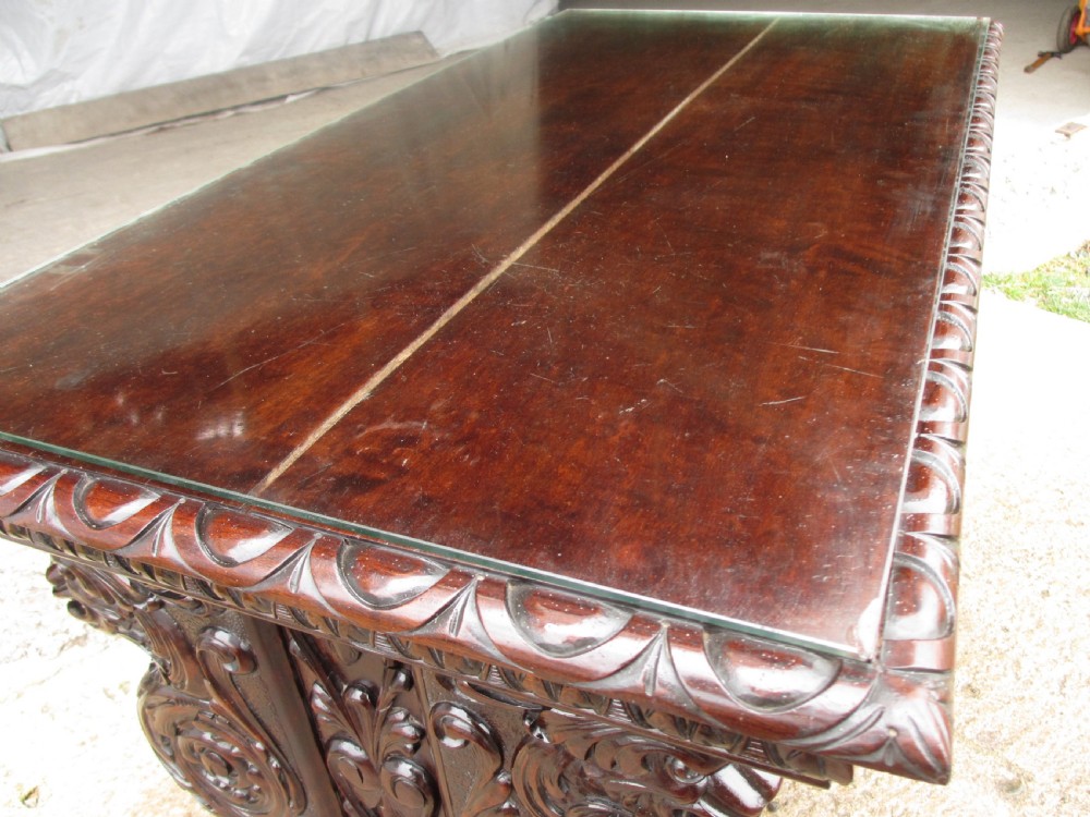Carved dark mahogany centre console table featuring scroll supports with carved grotesque figures, a decorated stretcher, and claw feet. View III