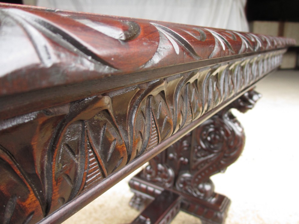 Carved dark mahogany centre console table featuring scroll supports with carved grotesque figures, a decorated stretcher, and claw feet. View V