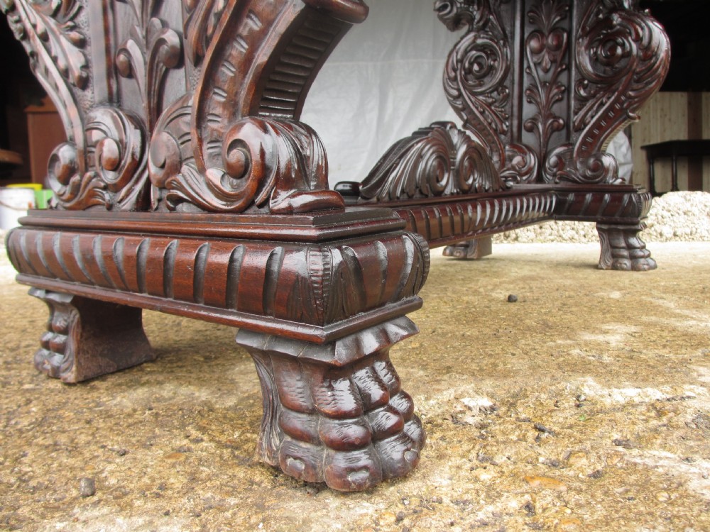 Carved dark mahogany centre console table featuring scroll supports with carved grotesque figures, a decorated stretcher, and claw feet. View VII