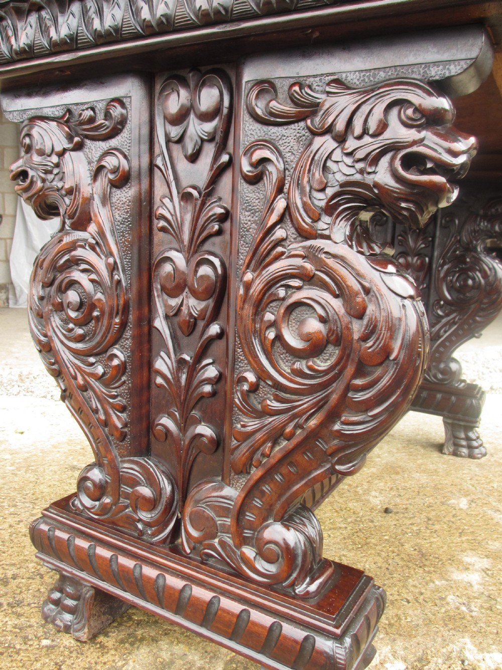 Carved dark mahogany centre console table featuring scroll supports with carved grotesque figures, a decorated stretcher, and claw feet. View X