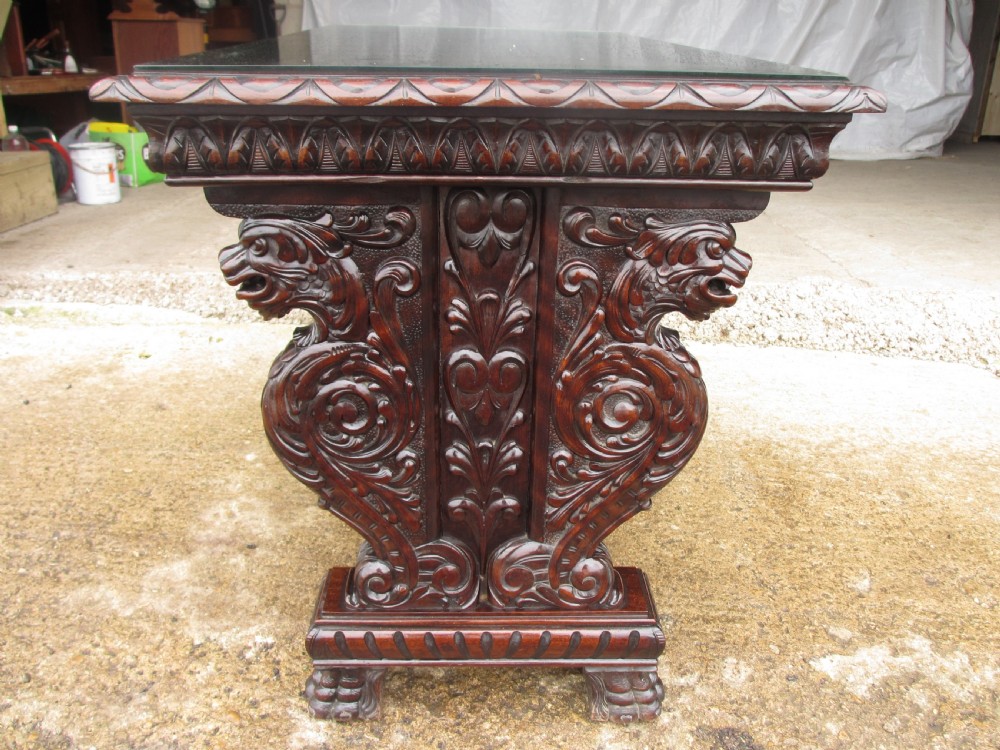 Carved dark mahogany centre console table featuring scroll supports with carved grotesque figures, a decorated stretcher, and claw feet. View XI