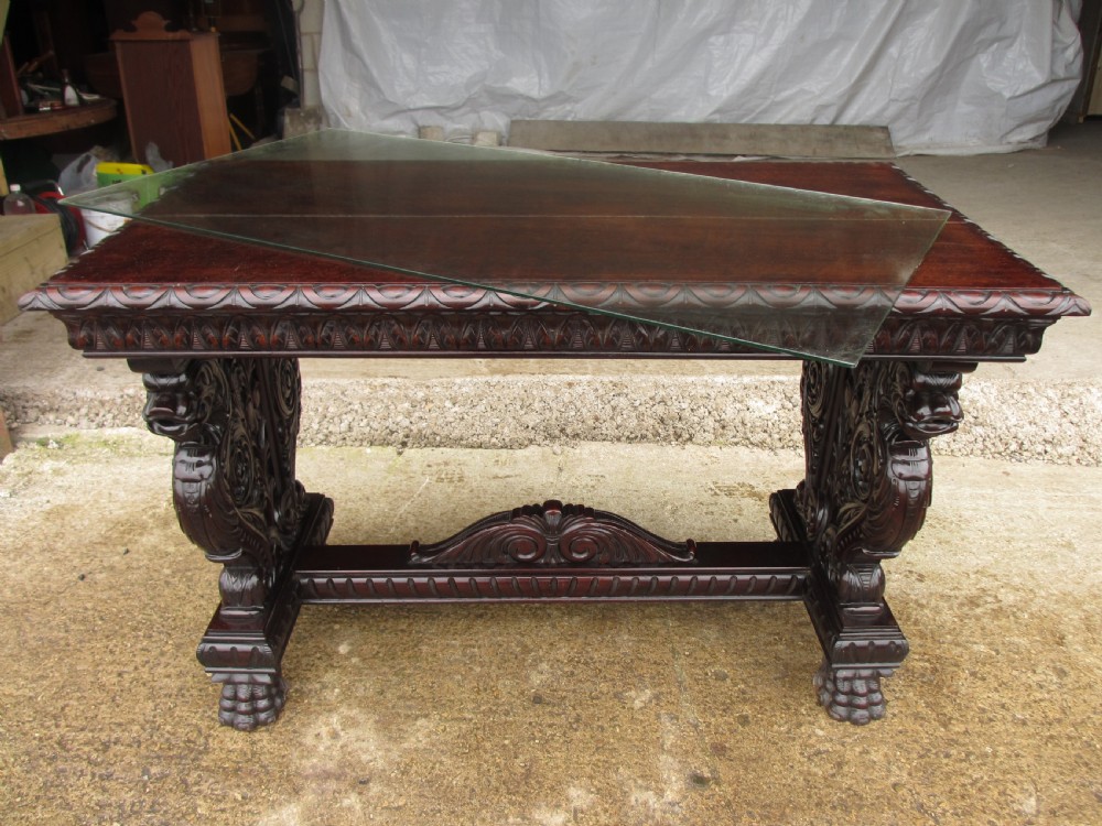 Carved dark mahogany centre console table featuring scroll supports with carved grotesque figures, a decorated stretcher, and claw feet. View XII