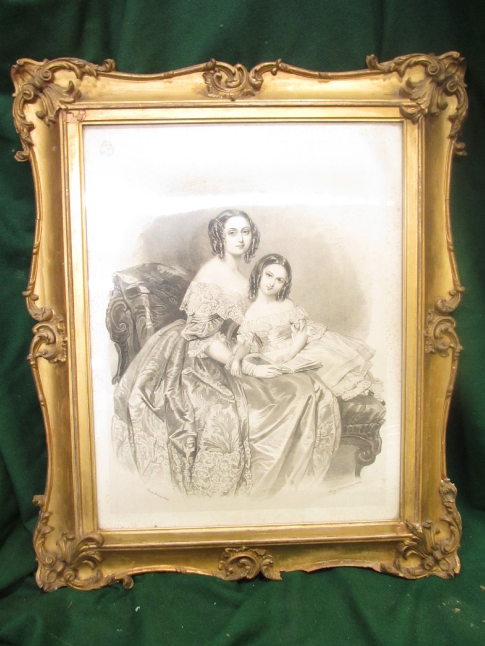 A rectangular gold gilt frame with ornate scroll detailing containing a monochrome portrait drawing of a mother and daughter.