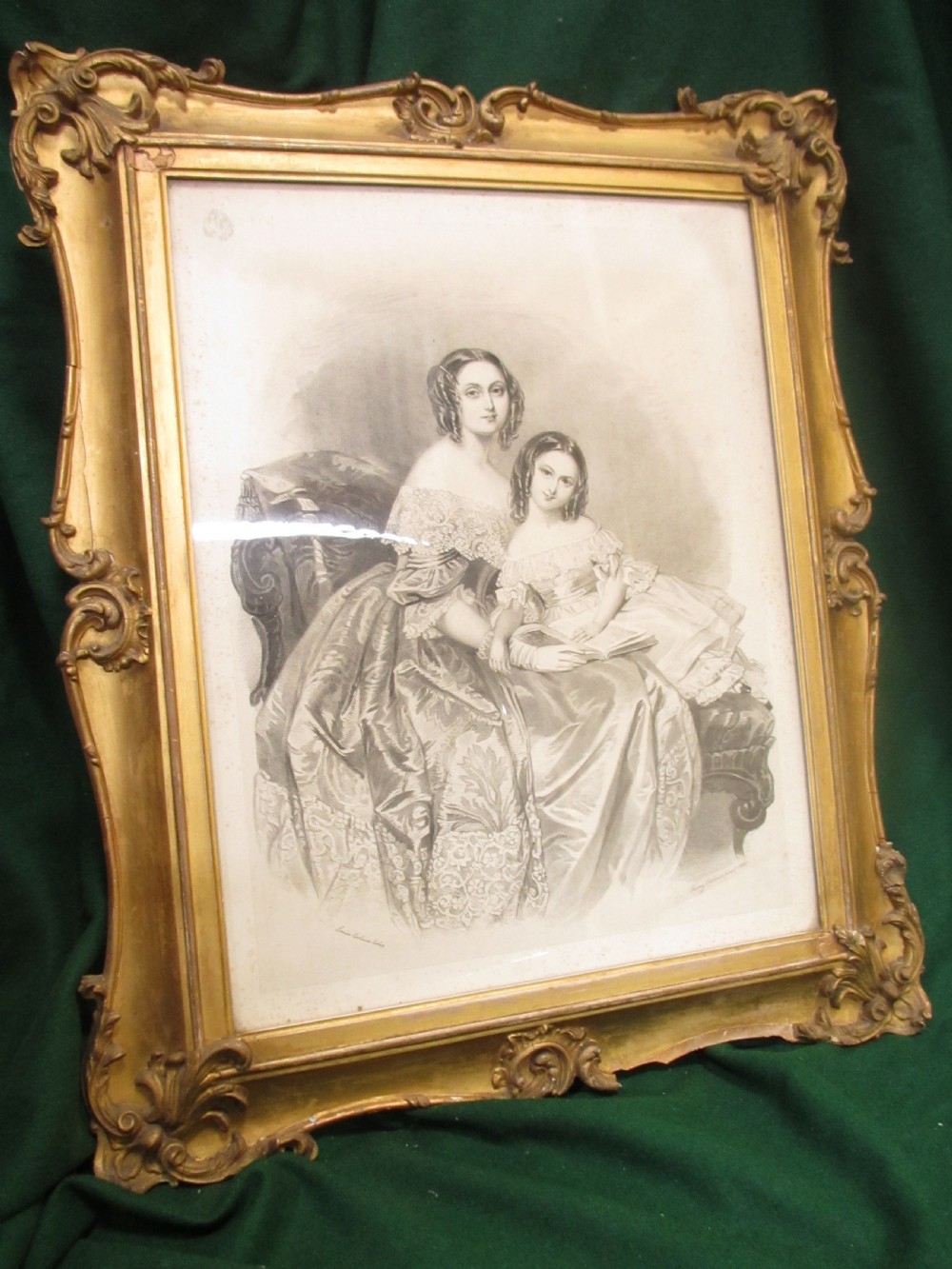 A rectangular gold gilt frame with ornate scroll detailing containing a monochrome portrait drawing of a mother and daughter. View II