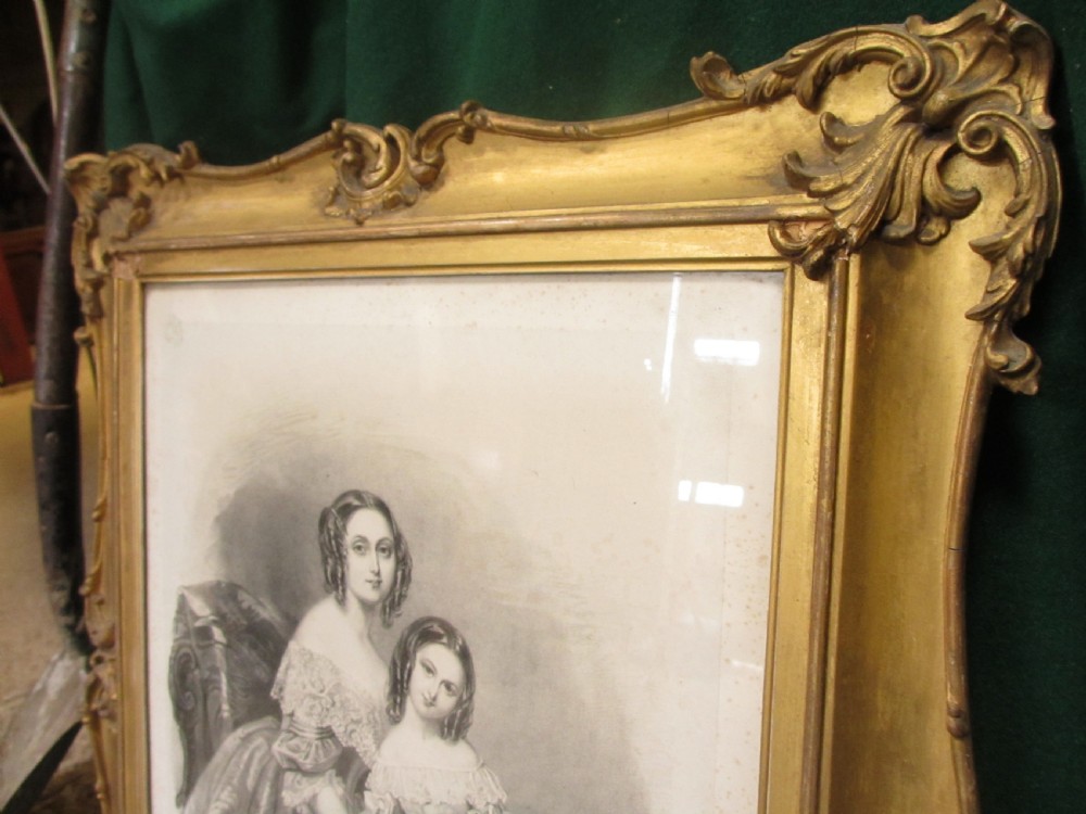 A rectangular gold gilt frame with ornate scroll detailing containing a monochrome portrait drawing of a mother and daughter. View III