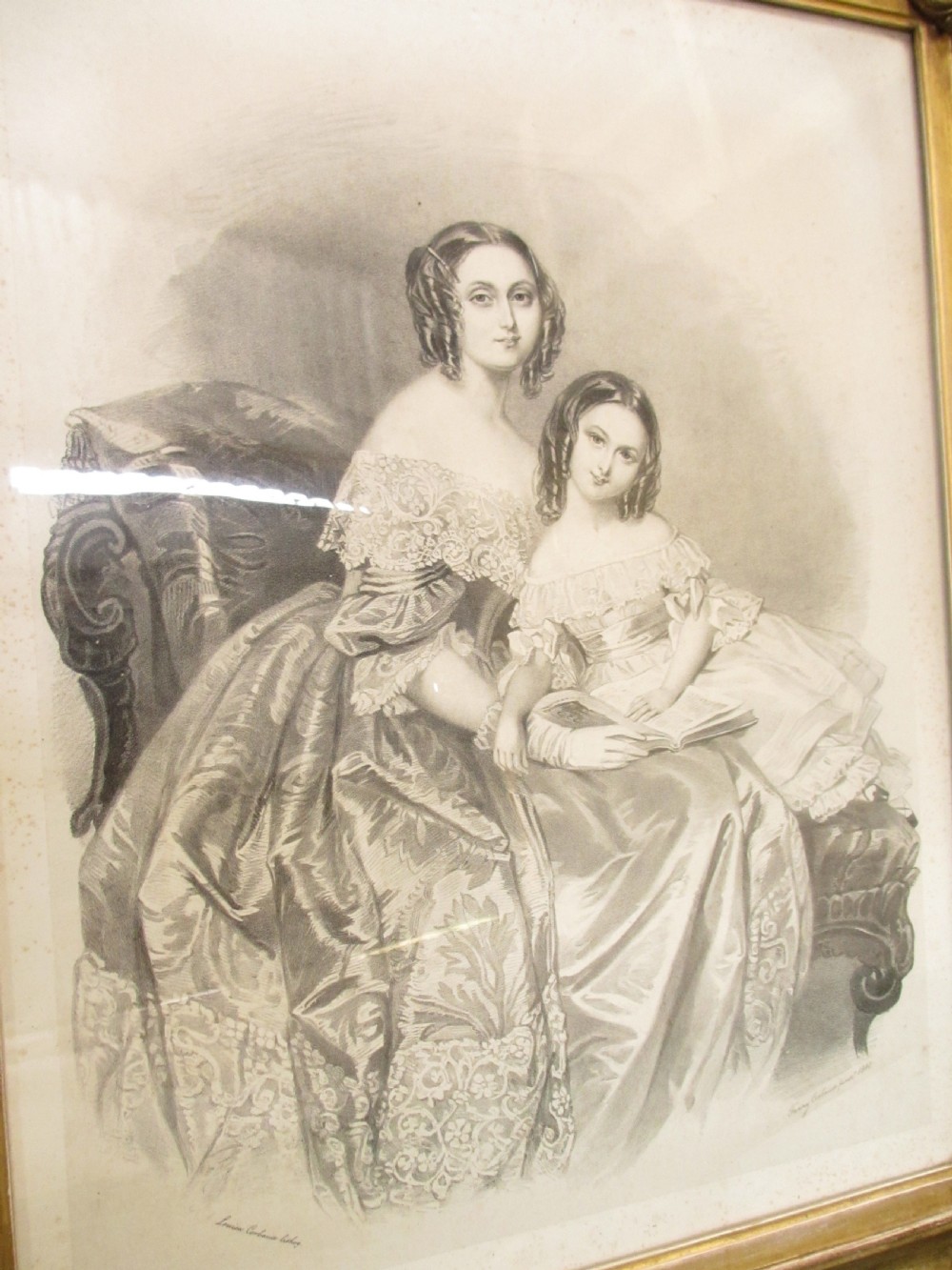 A rectangular gold gilt frame with ornate scroll detailing containing a monochrome portrait drawing of a mother and daughter. View V