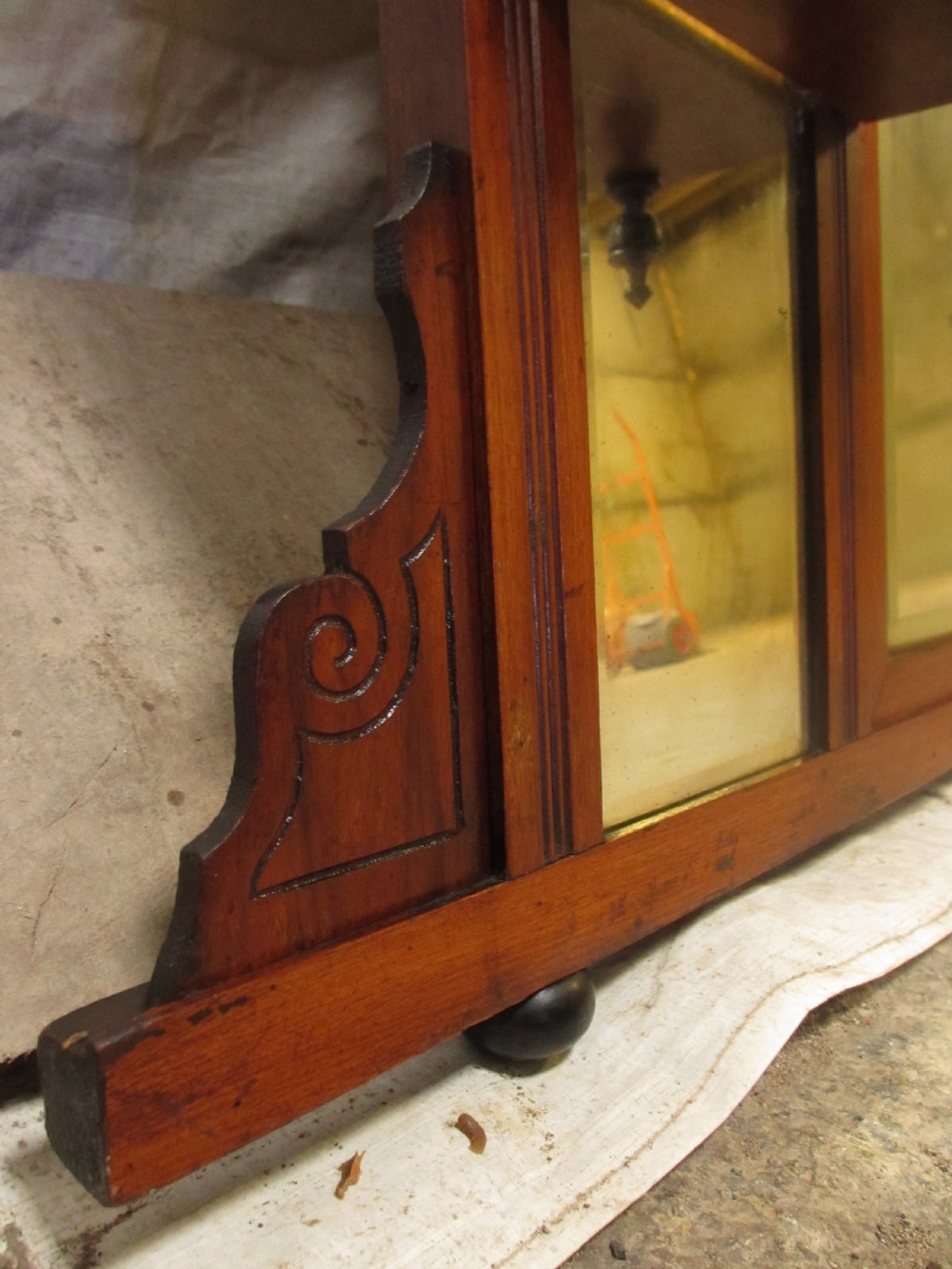 A carved mahogany Victorian overmantel mirror featuring multiple glass panels, side display shelves, turned spindle pillars, and stylised foliage carving. View V