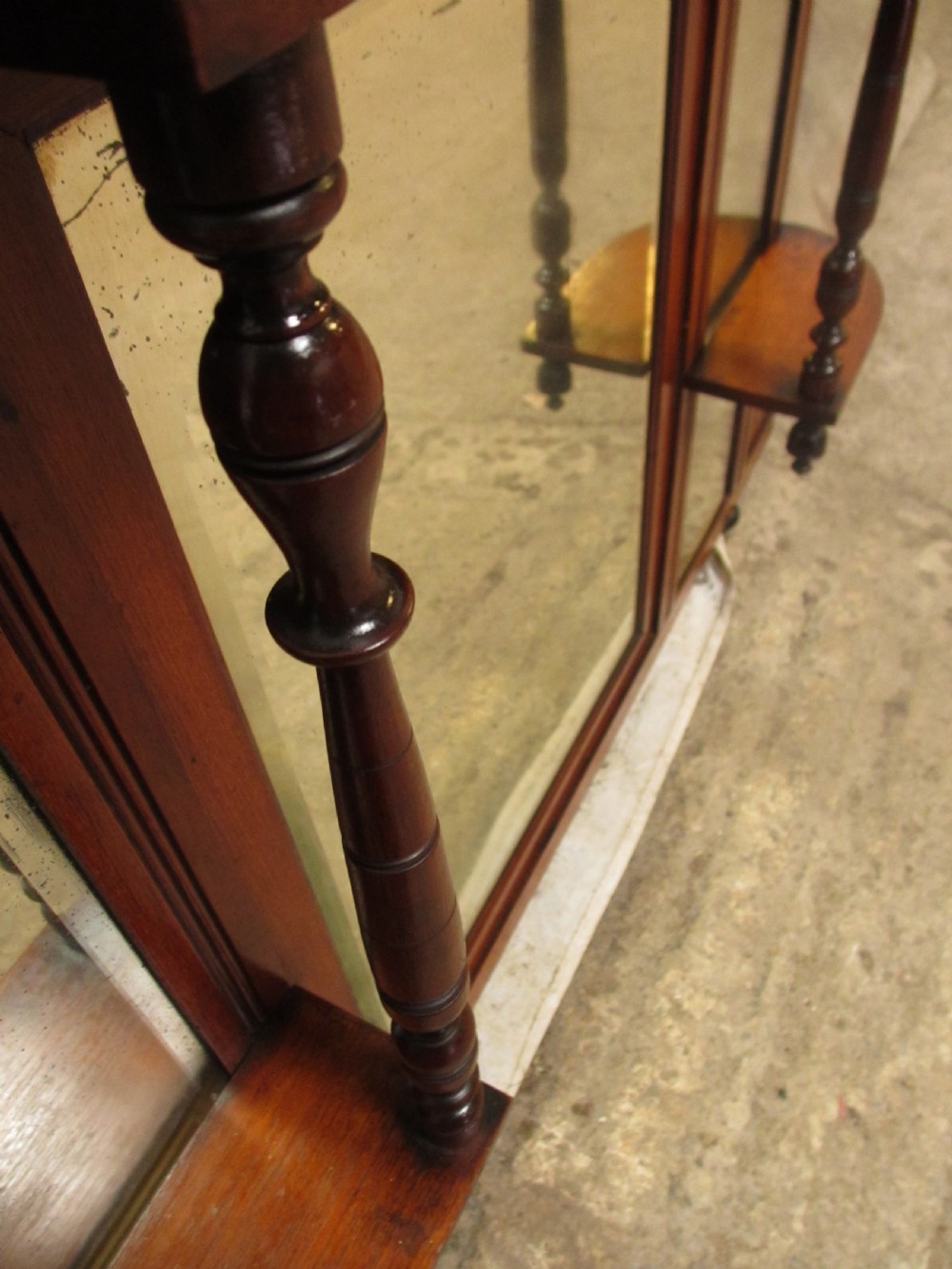 A carved mahogany Victorian overmantel mirror featuring multiple glass panels, side display shelves, turned spindle pillars, and stylised foliage carving. View VI