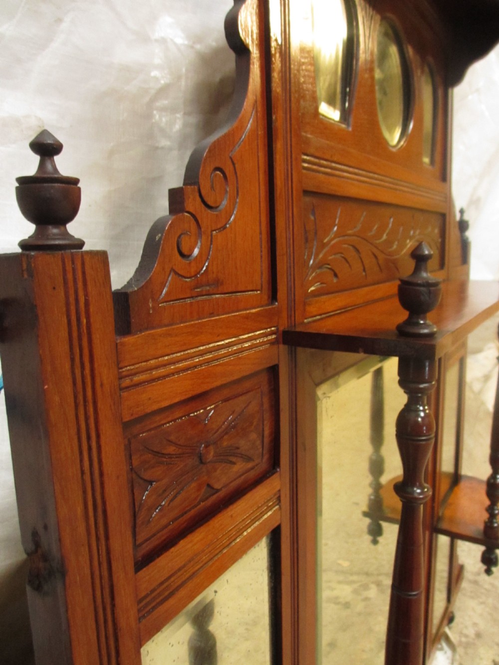 A carved mahogany Victorian overmantel mirror featuring multiple glass panels, side display shelves, turned spindle pillars, and stylised foliage carving. View VII