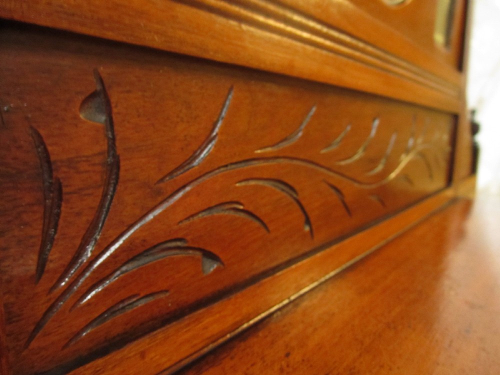 A carved mahogany Victorian overmantel mirror featuring multiple glass panels, side display shelves, turned spindle pillars, and stylised foliage carving. View VIII
