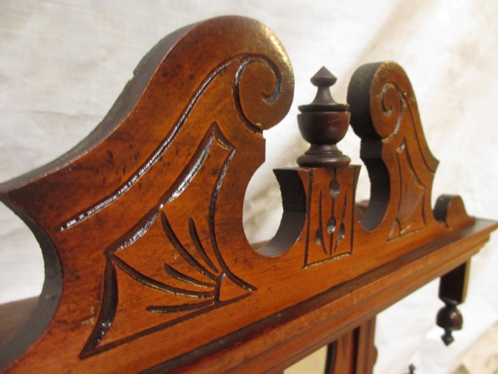 A carved mahogany Victorian overmantel mirror featuring multiple glass panels, side display shelves, turned spindle pillars, and stylised foliage carving. View X