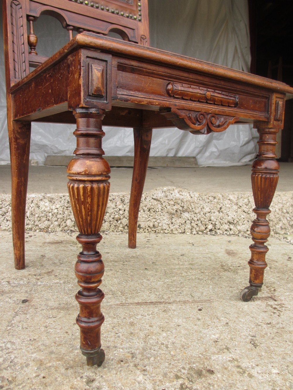 A set of Victorian dining chairs featuring embossed floral leather backrests and seats, brass top handles, turned front legs with castors, and studding detail. View VIII
