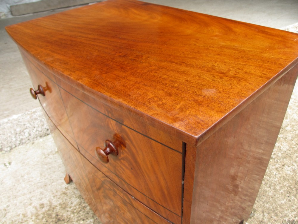 A Georgian flame mahogany bow-fronted pot commode featuring decorative string inlay, turned wooden knobs, and splayed bracket feet. View III