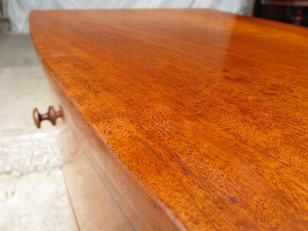 A Georgian flame mahogany bow-fronted pot commode featuring decorative string inlay, turned wooden knobs, and splayed bracket feet. View IV