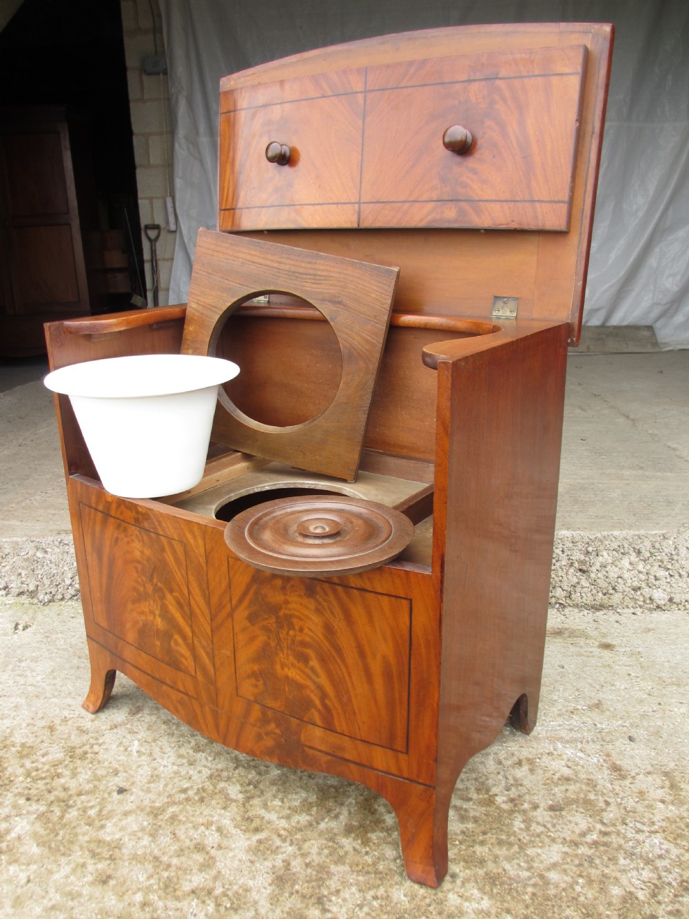A Georgian flame mahogany bow-fronted pot commode featuring decorative string inlay, turned wooden knobs, and splayed bracket feet. View VIII