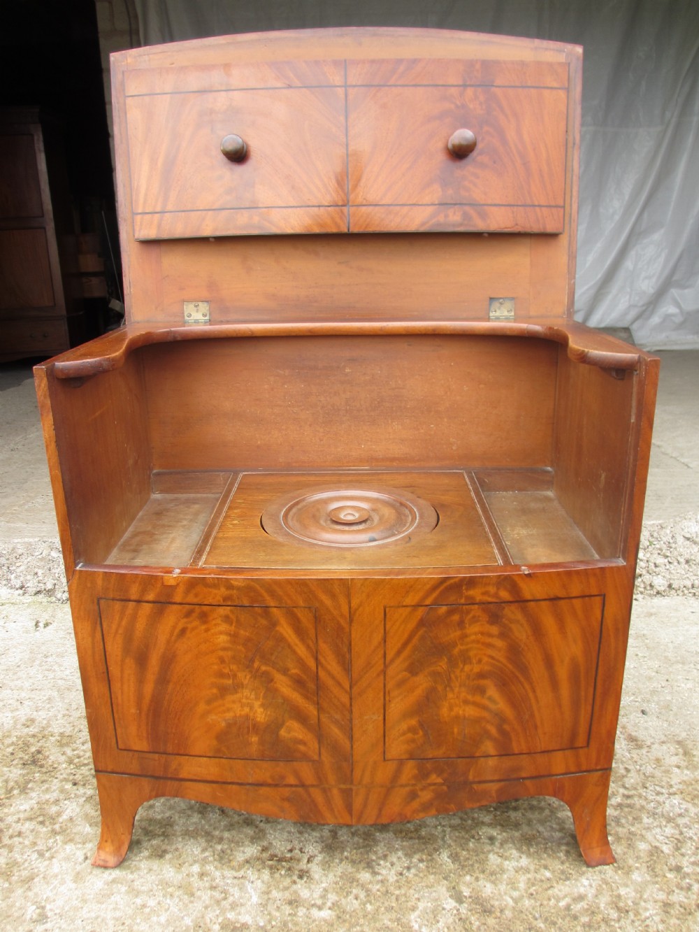 A Georgian flame mahogany bow-fronted pot commode featuring decorative string inlay, turned wooden knobs, and splayed bracket feet. View IX