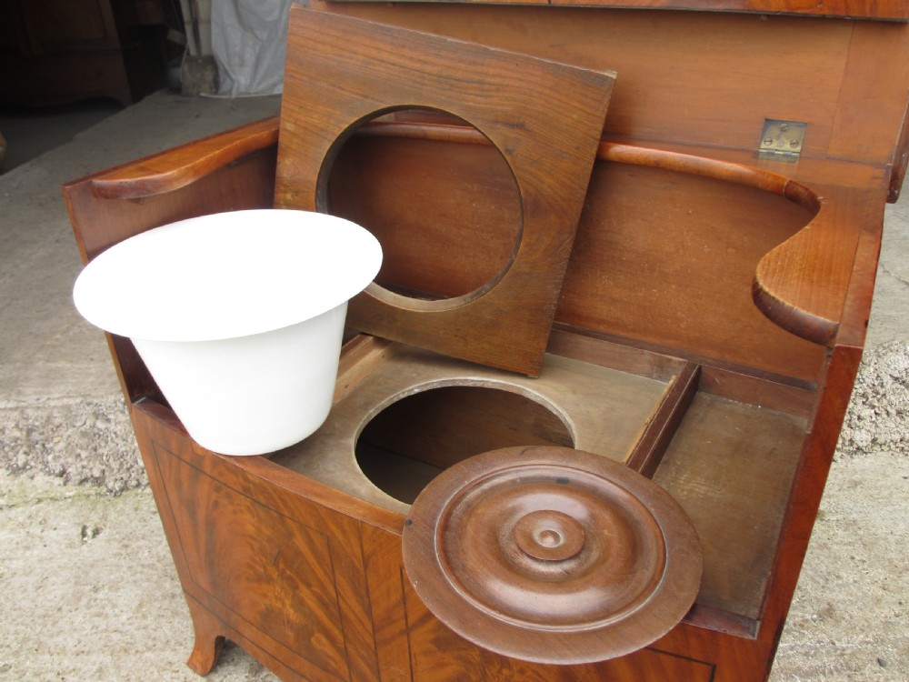 A Georgian flame mahogany bow-fronted pot commode featuring decorative string inlay, turned wooden knobs, and splayed bracket feet. View X