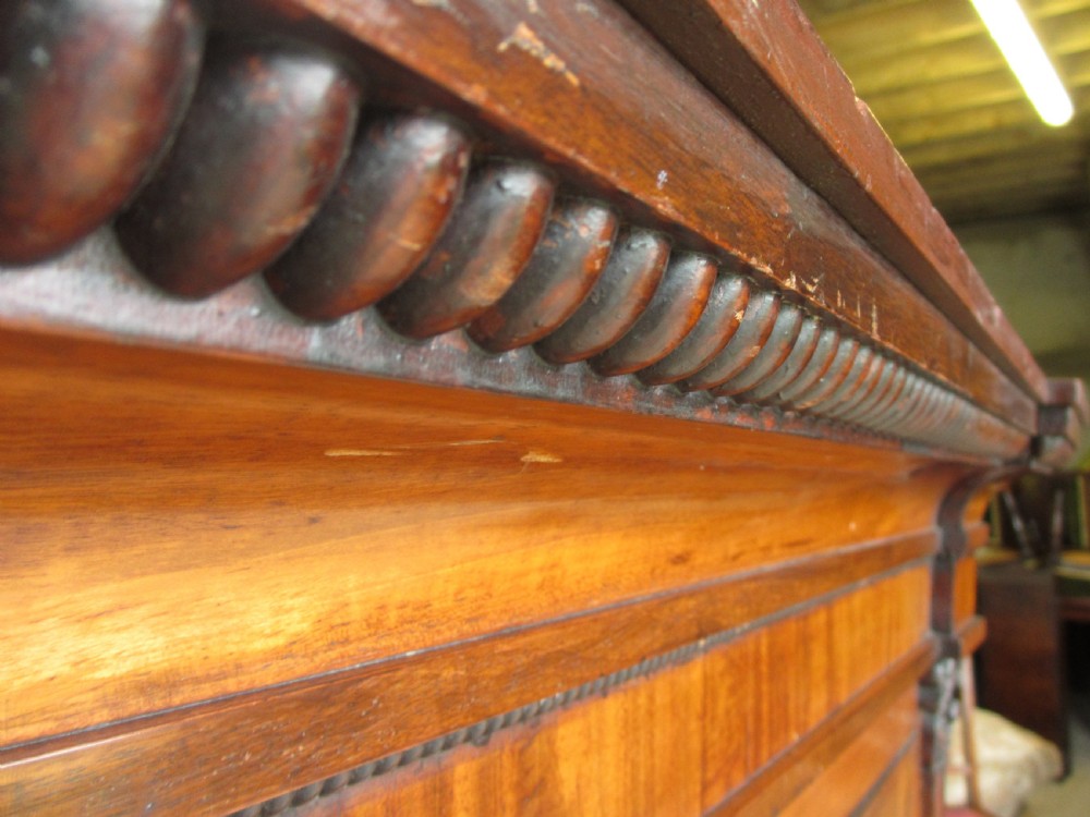A Georgian flame mahogany two-door cabinet featuring fluted side pilasters, carved capitals, and prominent timber grain on the panelled doors. View V