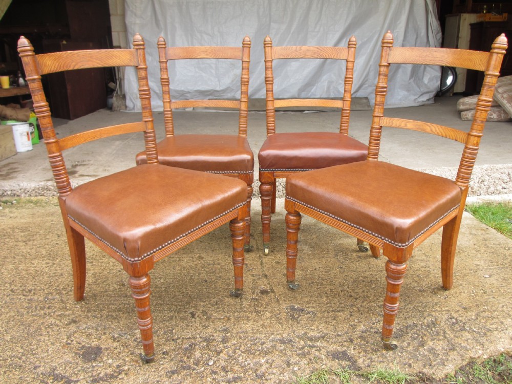 A set of four Victorian oak dining chairs featuring brown leather studded seats and turned wooden legs with brass castors. View III