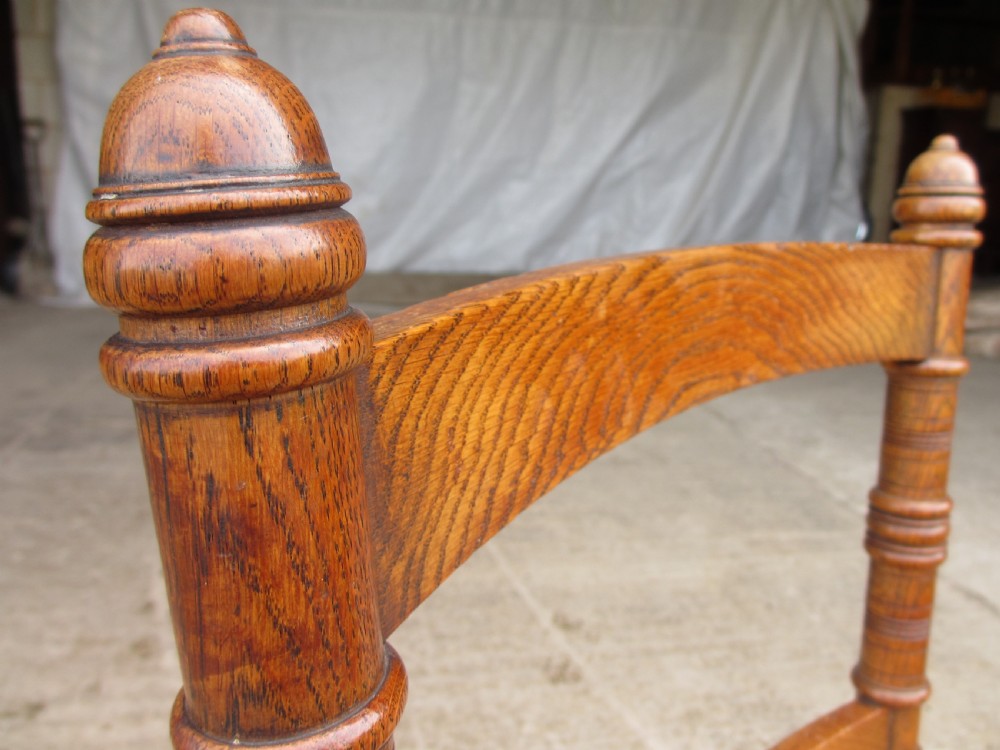 A set of four Victorian oak dining chairs featuring brown leather studded seats and turned wooden legs with brass castors. View VI