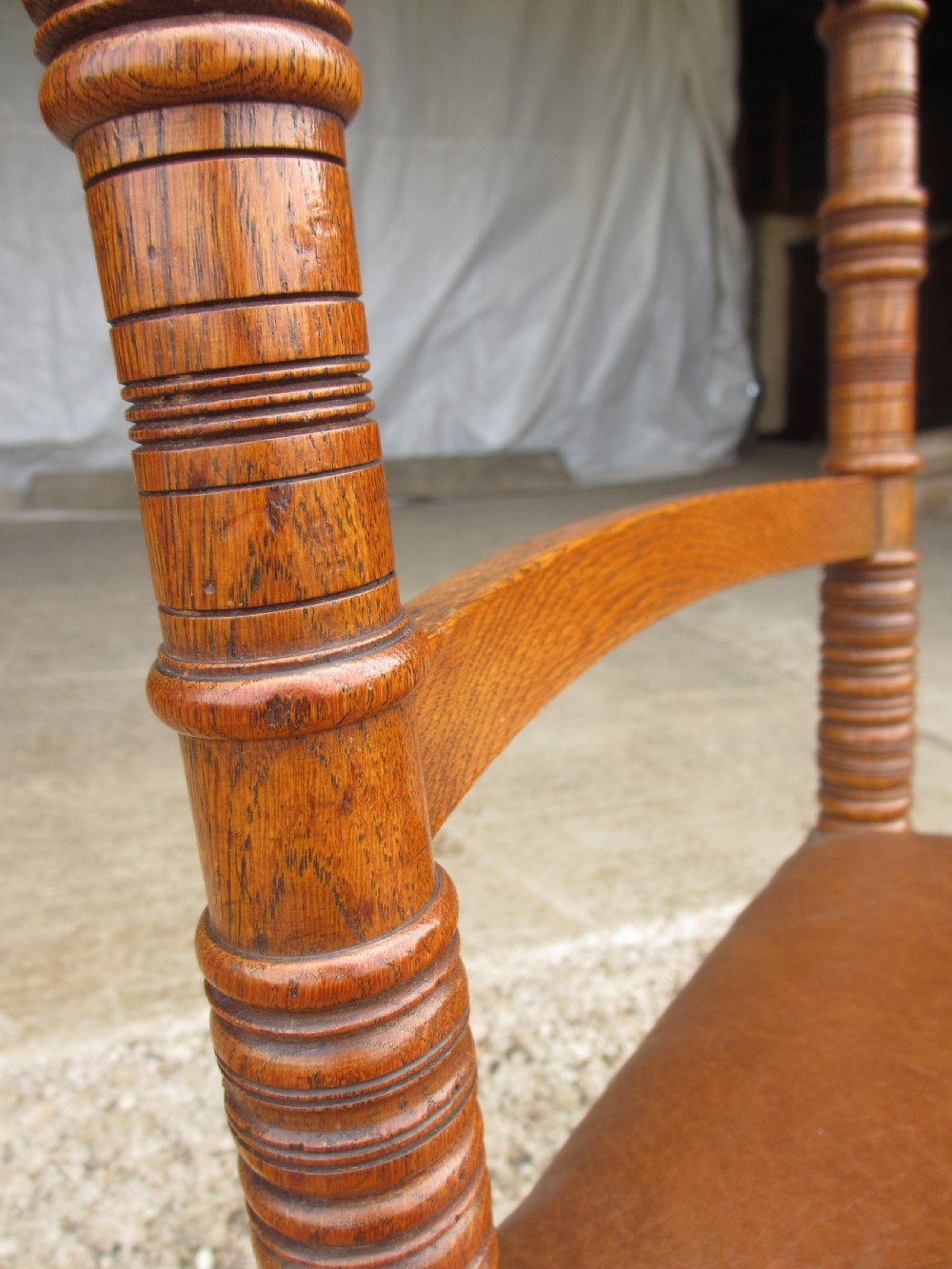A set of four Victorian oak dining chairs featuring brown leather studded seats and turned wooden legs with brass castors. View VII