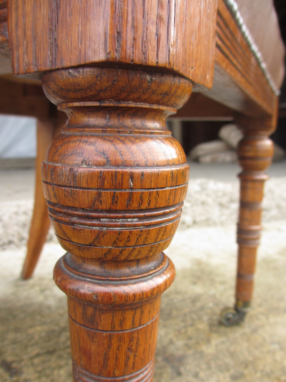 A set of four Victorian oak dining chairs featuring brown leather studded seats and turned wooden legs with brass castors. View XI